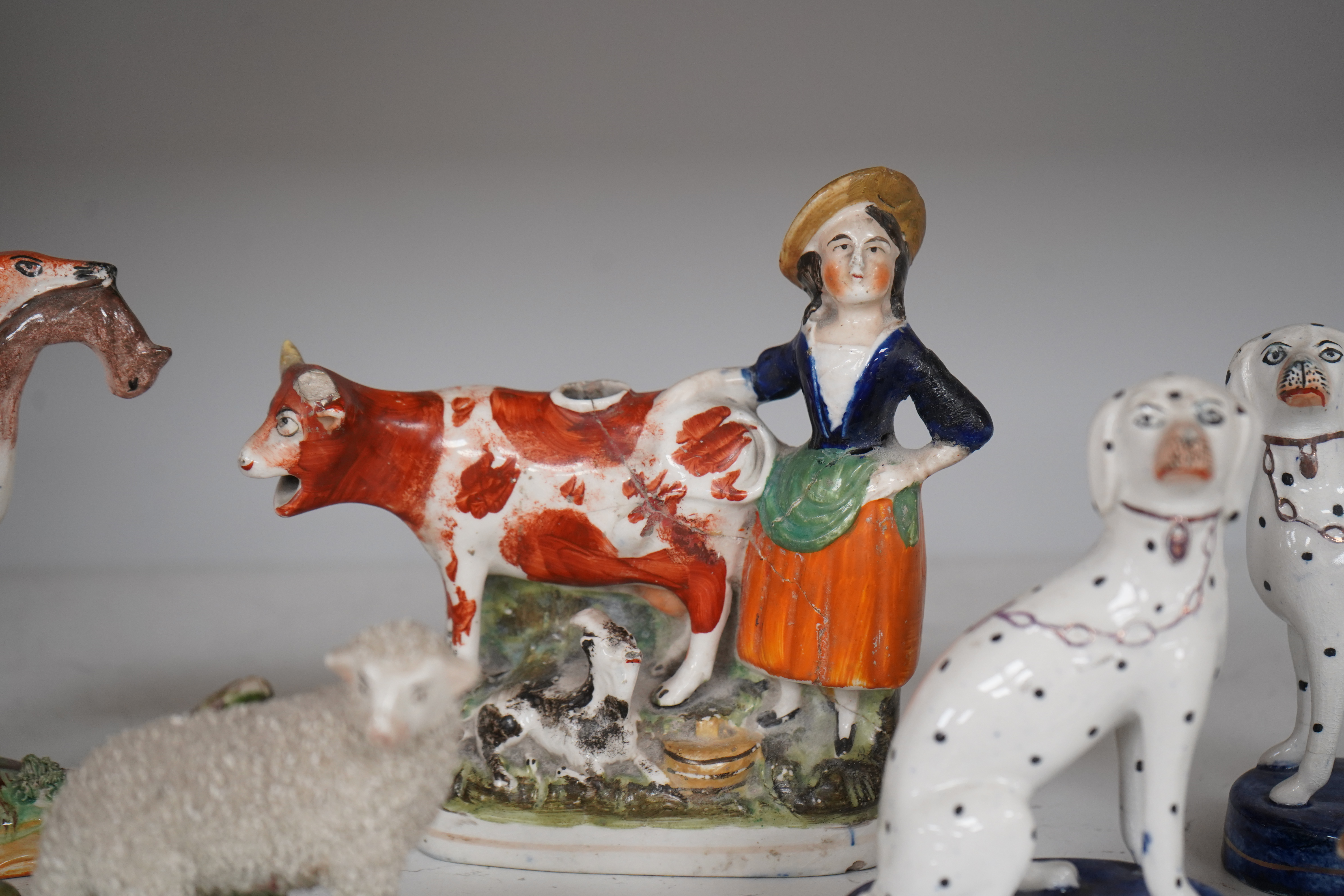 Eight Staffordshire figures to include a pair of Dalmatian’s and a cow creamer figure, largest 18cm wide. Condition - varies, poor to good